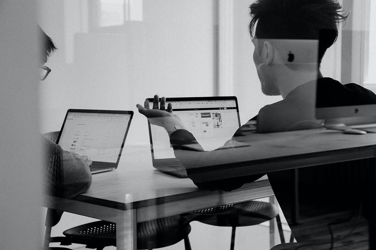 Black and white photograph of two devleopers in a meeting with a laptop
